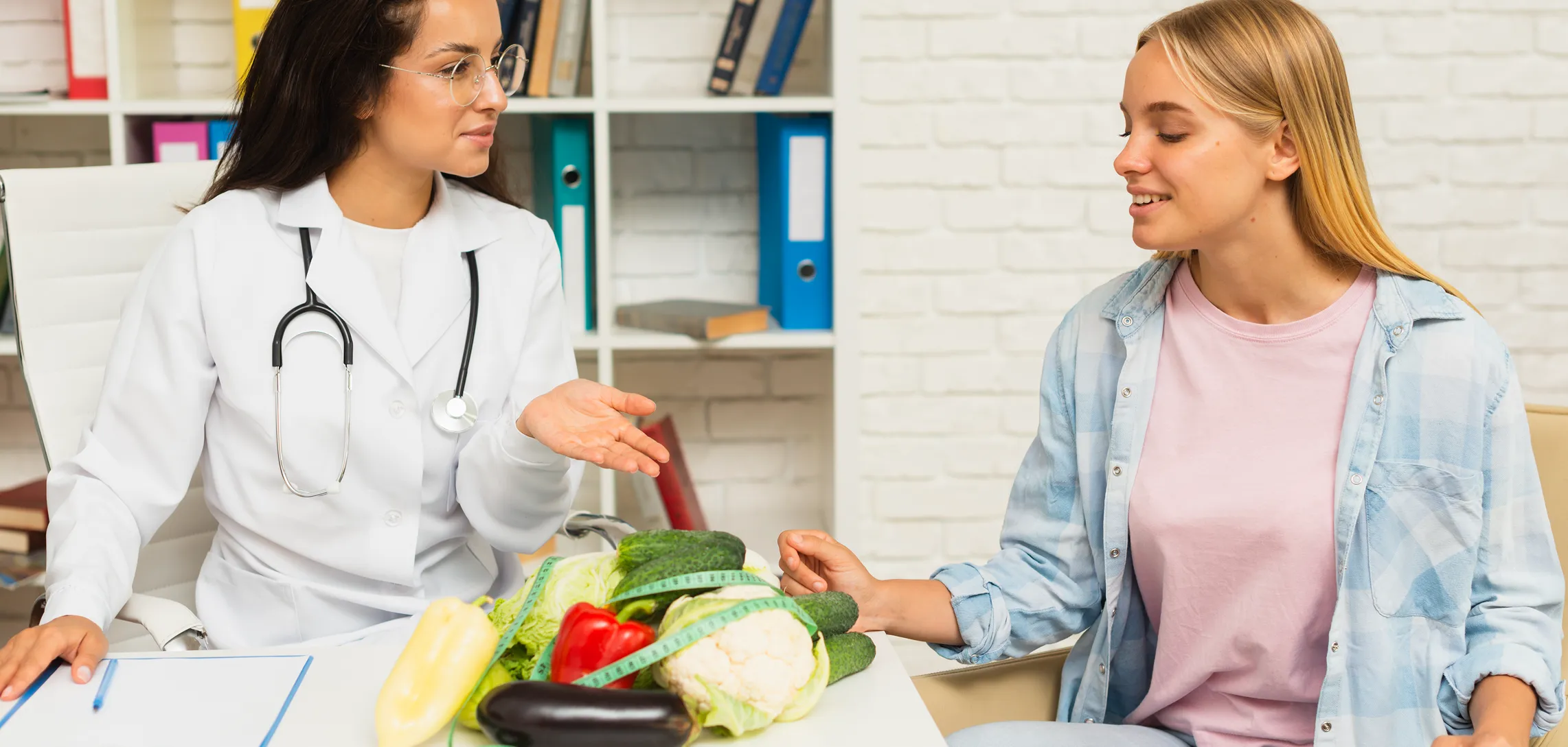 A nutritionist talking a client through a plate of fresh vegetables